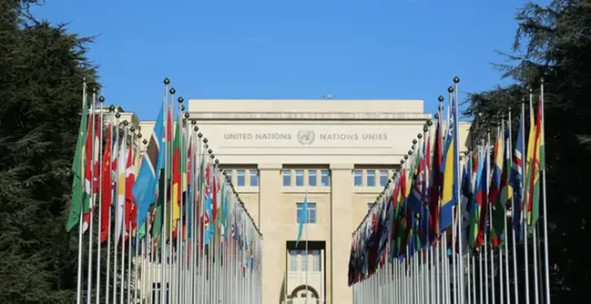 En stor byggnad med många flaggor framför sig.