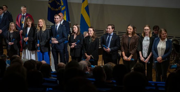 studenter på rad i en sal med examensdiplom