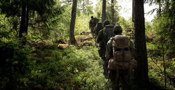 Soldater marscherar på rad i skogen.